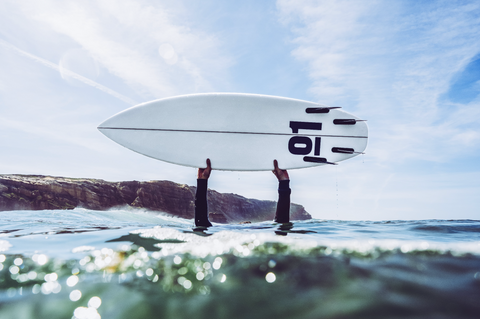 Custom surfboard in surfers' hands.