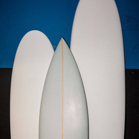 Two surfboard blanks and one smaller finished surfboard. 
